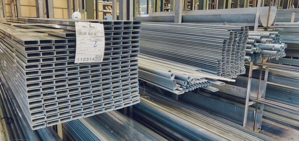 Tubi metallici impilati in un magazzino industriale.