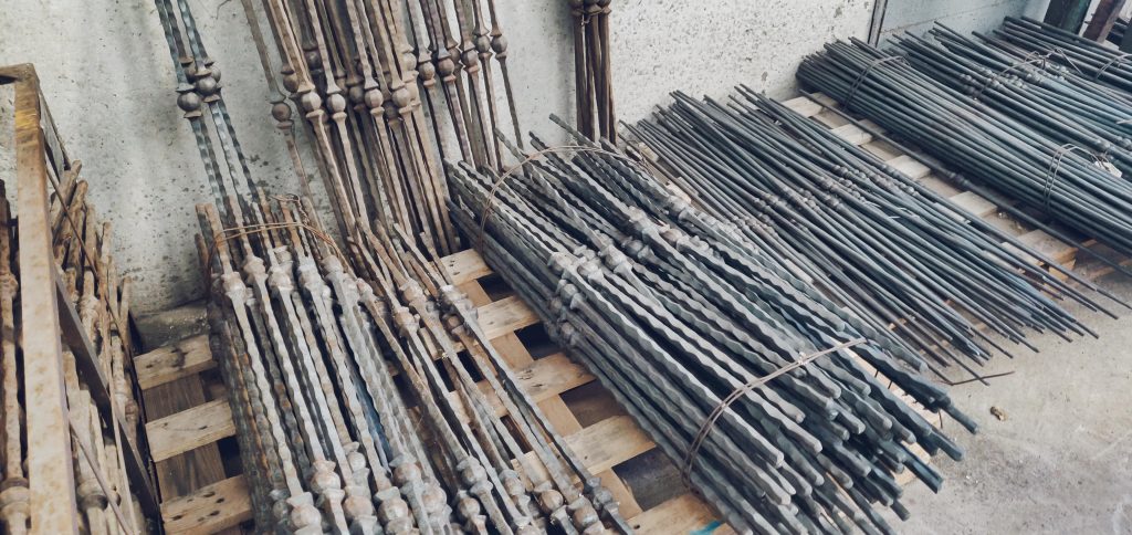 Barre di metallo accatastate su pallet di legno.